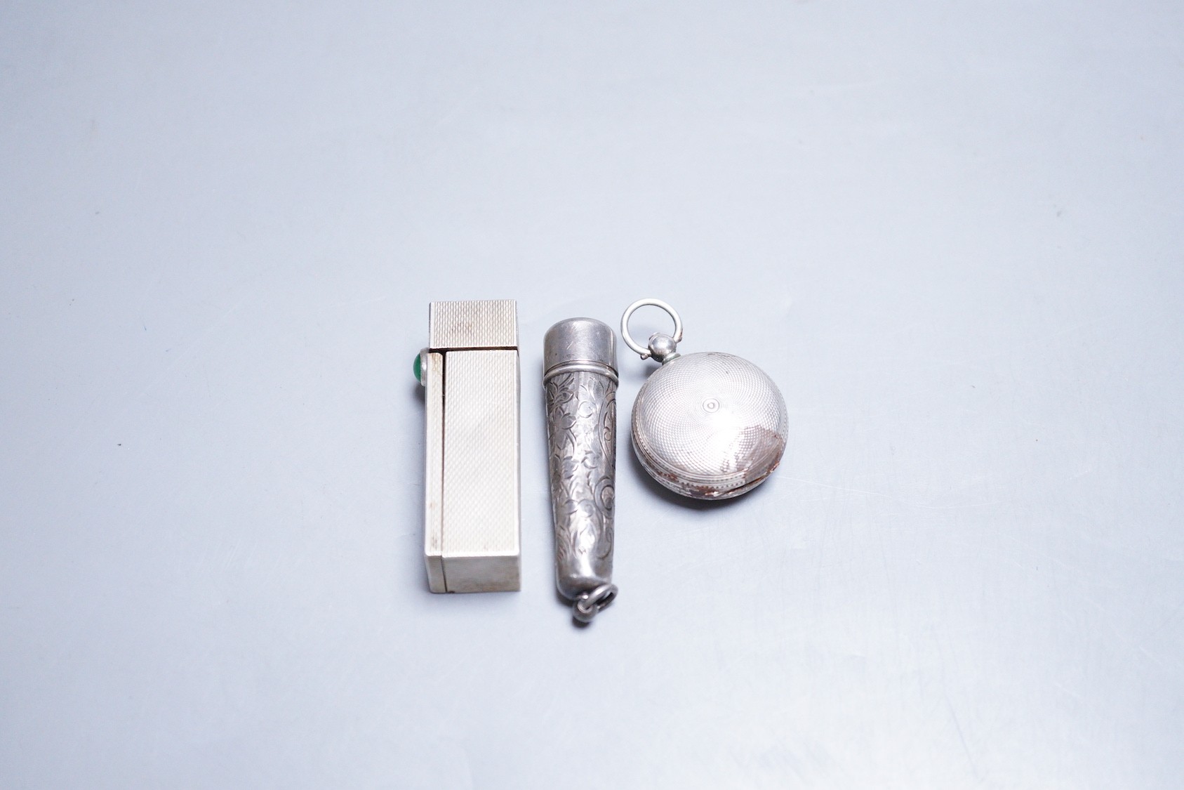 A late Victorian engine turned silver sovereign case(a.f.) Chester, 1886, a white metal and cabochon set lipstick holder and a silver cigarette holder case.